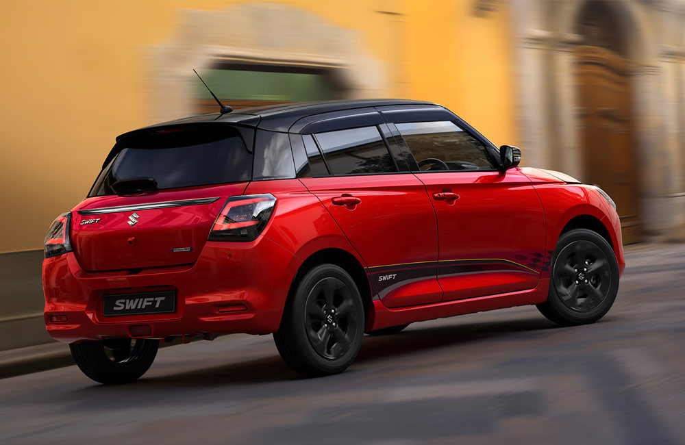 red suzuki swift driving through a street