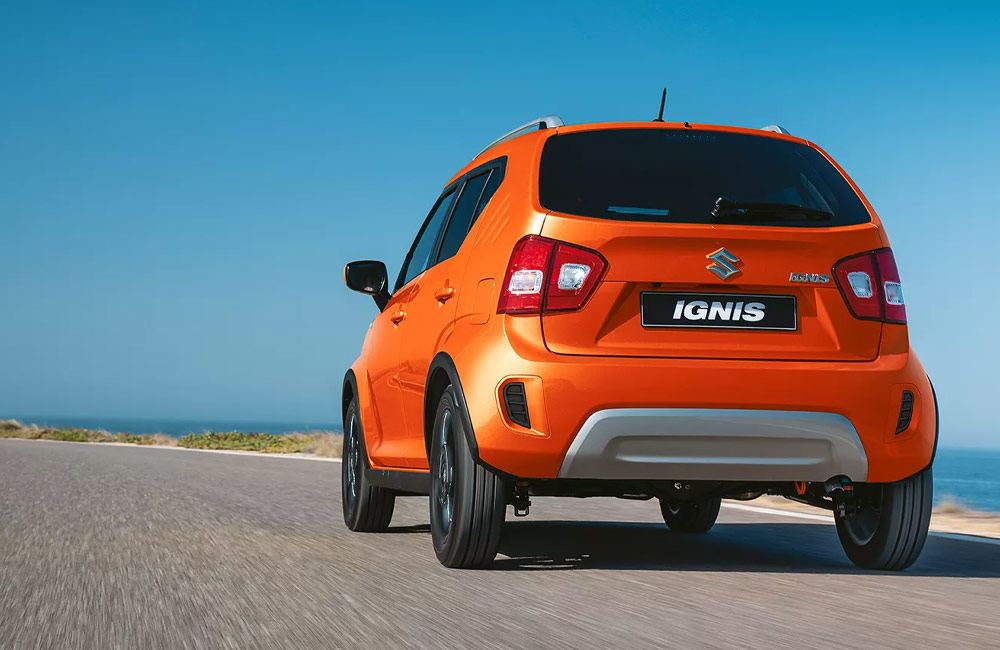 Orange Ignis driving on a road viewed from the rear